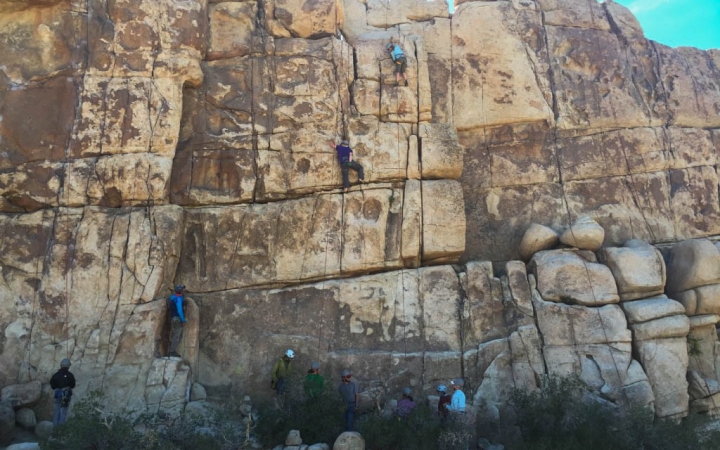 a group of rock climbers make their way up a rock wall on an outward bound course